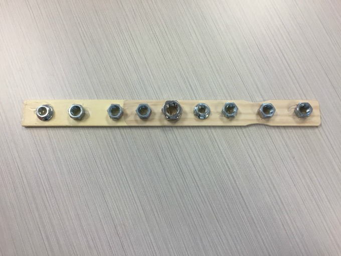 Turn a paint stir stick and bolts into a menorah to turn hardware into holiday decor - thediybungalow.com