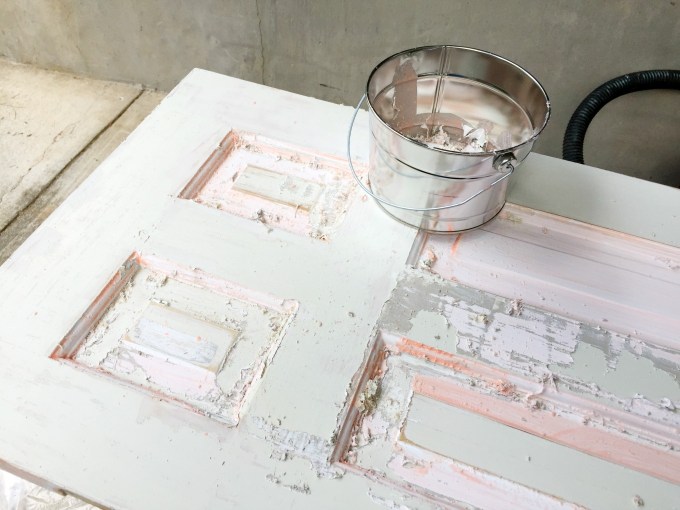 Once the chemical stripper has worked, scrape the paint off the door - thediybungalow.com