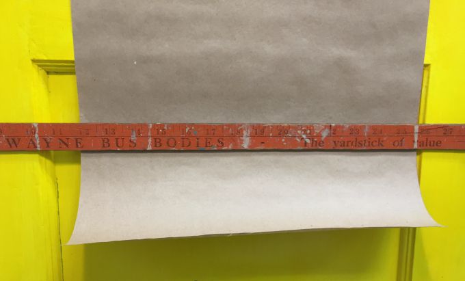 Yard stick holds the paper flat to the door - how to turn an old door into a memo board - thediybungalow.com